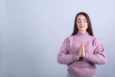 Photo of Young woman meditating on grey background, space for text. Stress relief exercise