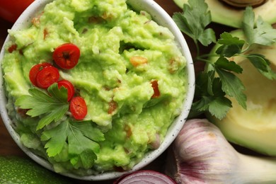 Delicious guacamole and ingredients on table, flat lay