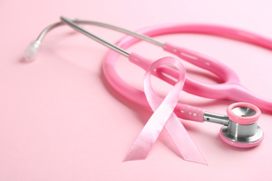 Photo of Pink ribbon and stethoscope on color background, closeup. Breast cancer concept