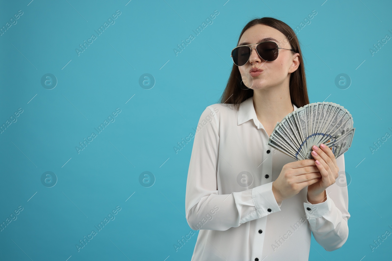 Photo of Woman with dollar banknotes on light blue background, space for text