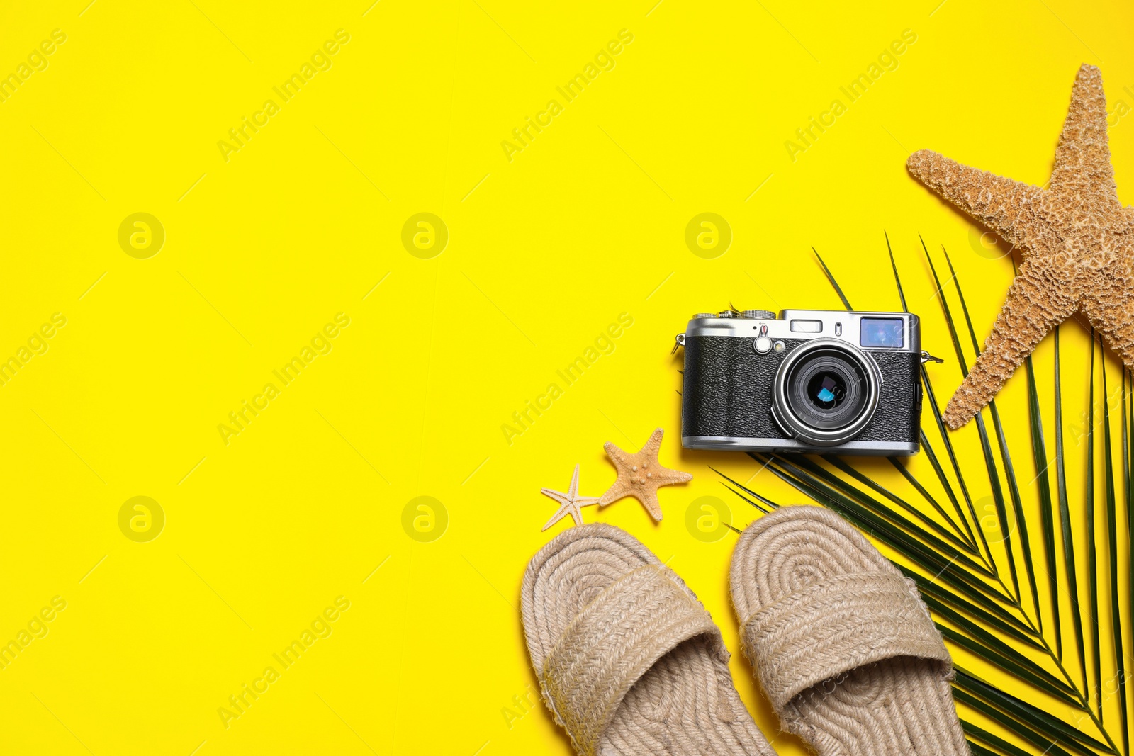 Photo of Beach accessories and palm leaf on yellow background, flat lay. Space for text