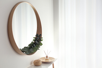 Photo of Round mirror with wooden frame in light room