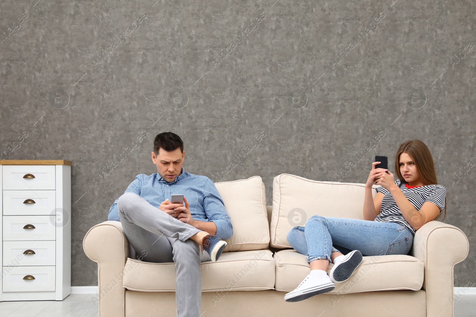 Photo of Couple engaged in smartphones while spending time together at home. Loneliness concept