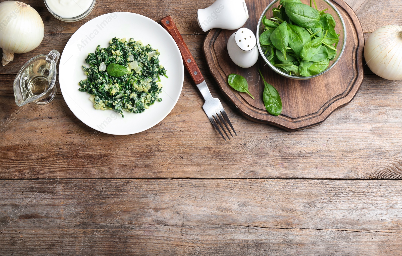 Photo of Flat lay composition with cooked spinach and space for text on wooden table. Healthy food