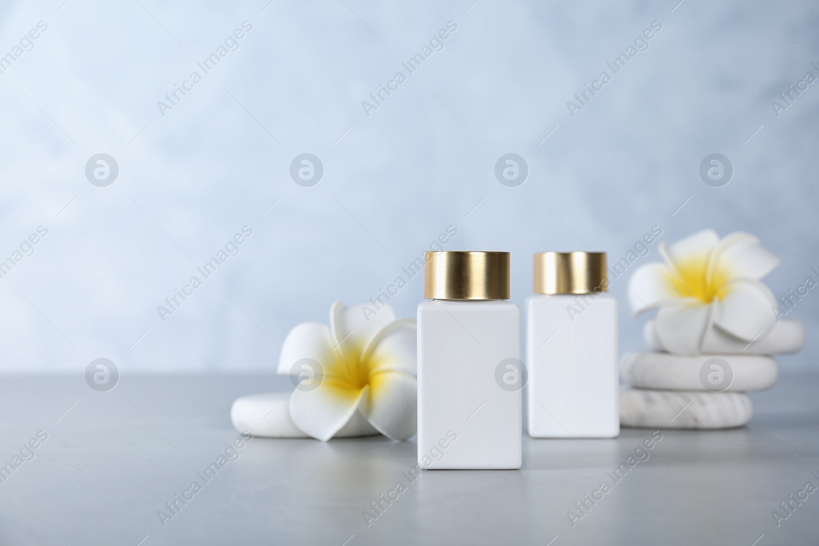 Photo of Cosmetic products, spa stones and tropical flowers on light grey table