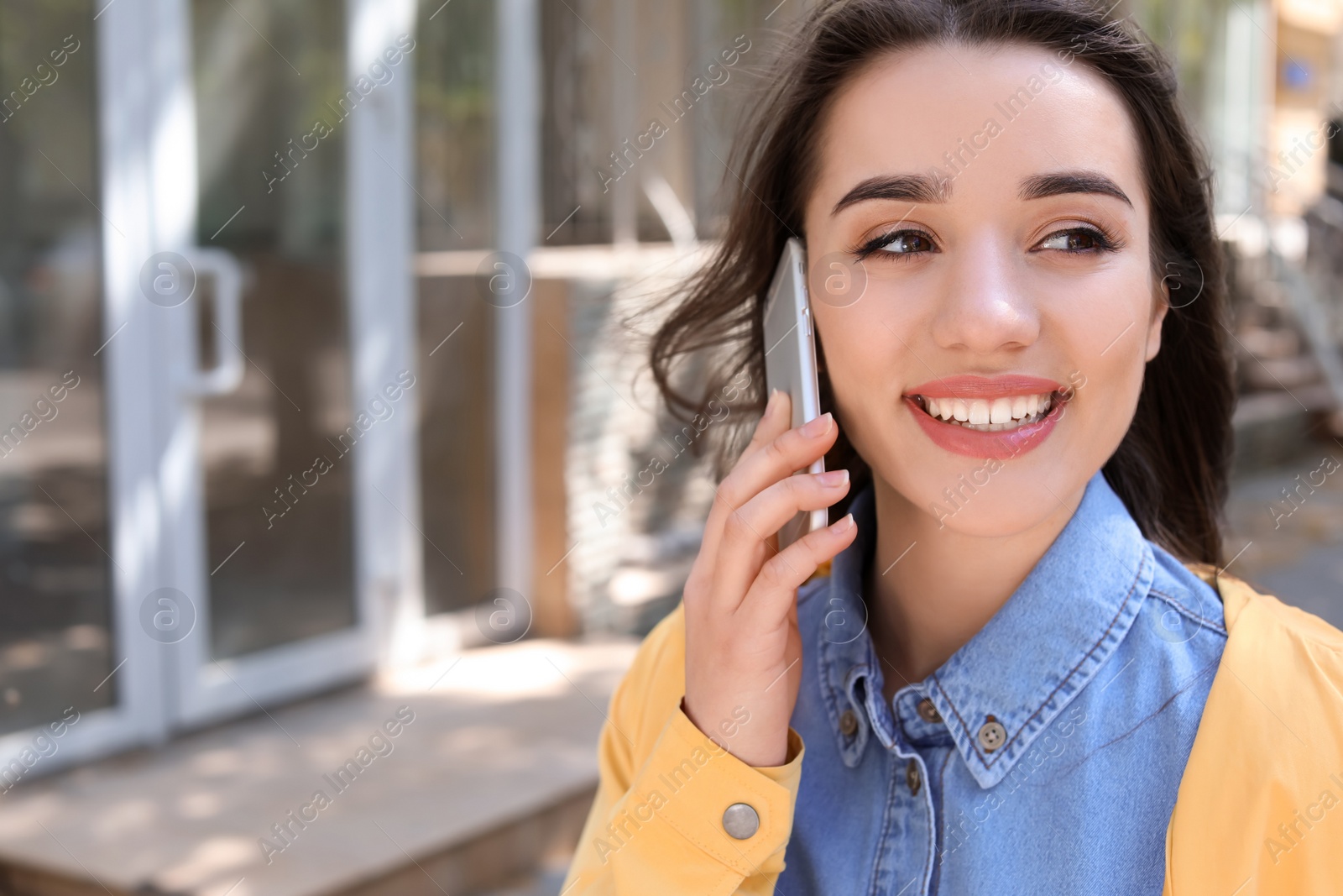 Photo of Young woman talking by phone outdoors on sunny day