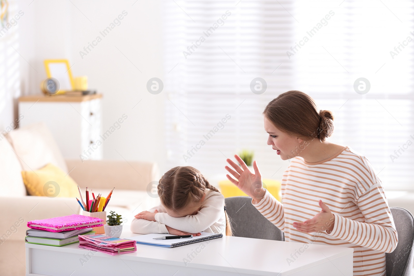 Photo of Mother scolding her daughter while helping with homework indoors