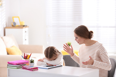 Mother scolding her daughter while helping with homework indoors