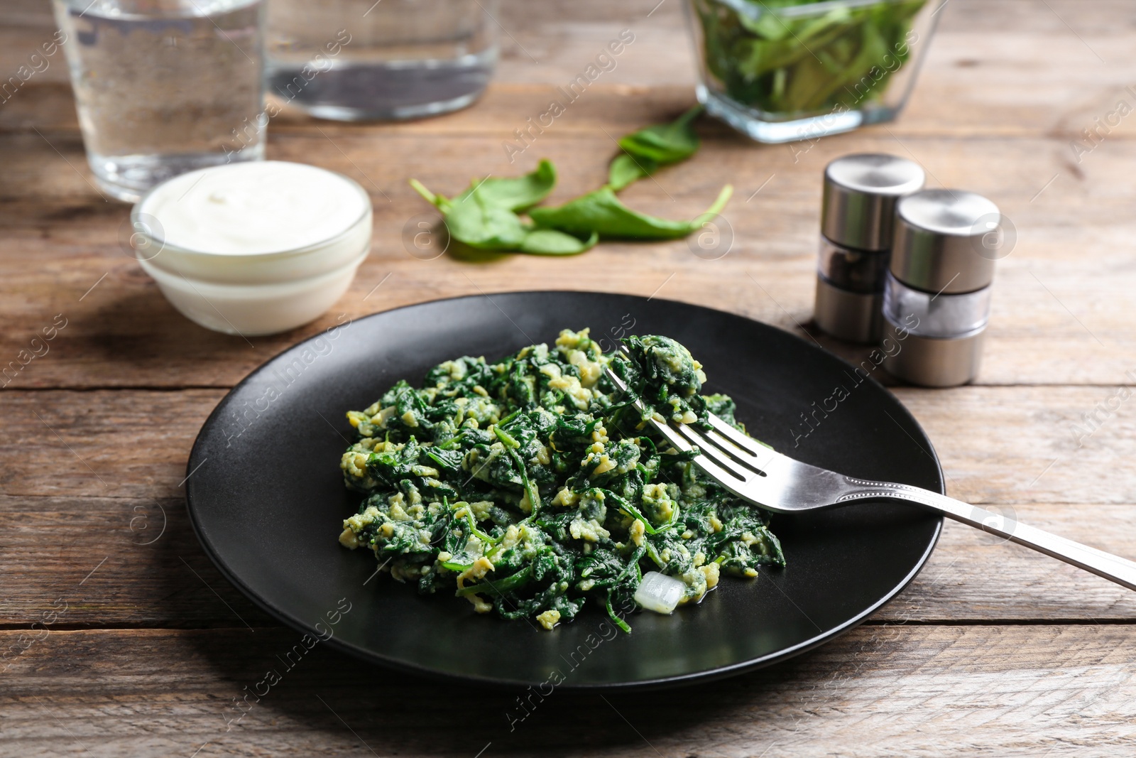 Photo of Tasty cooked spinach served on wooden table. Healthy food