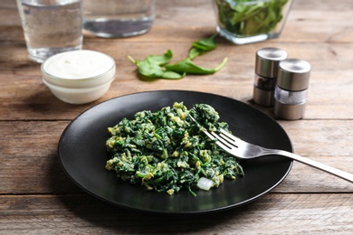 Photo of Tasty cooked spinach served on wooden table. Healthy food