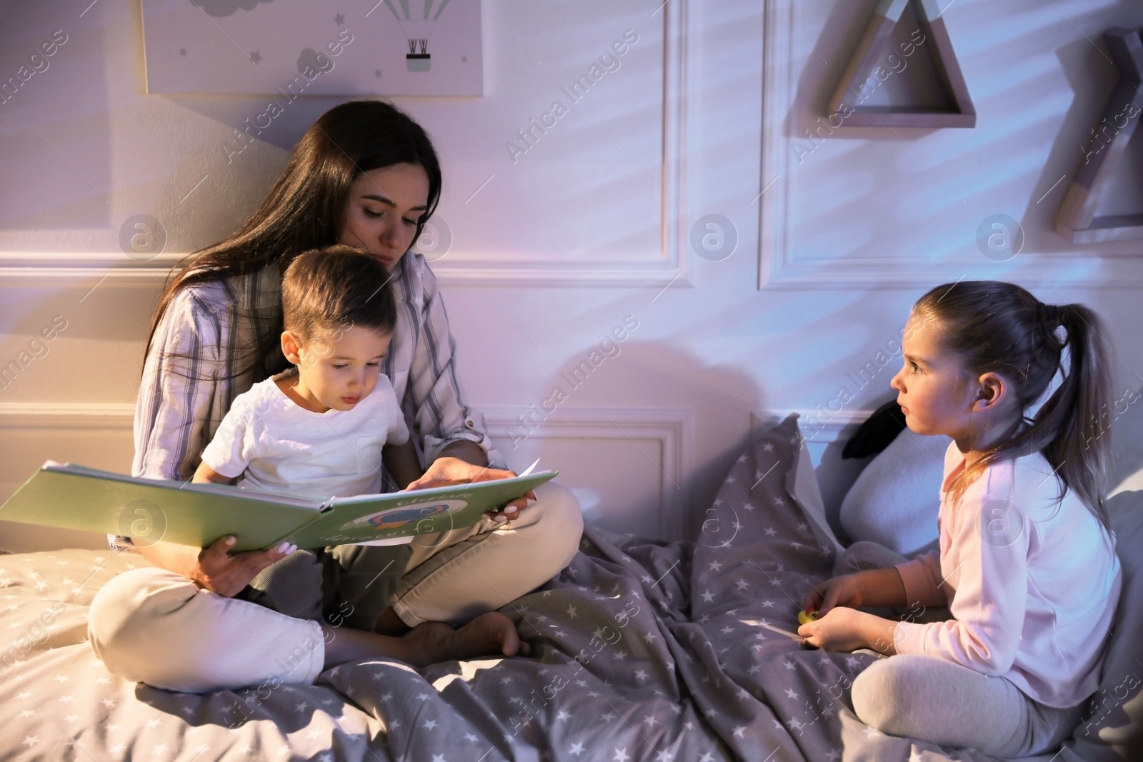 Photo of Mother reading bedtime story to her children at home