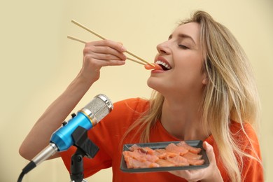 Photo of Food blogger eating in front of microphone against light background. Mukbang vlog