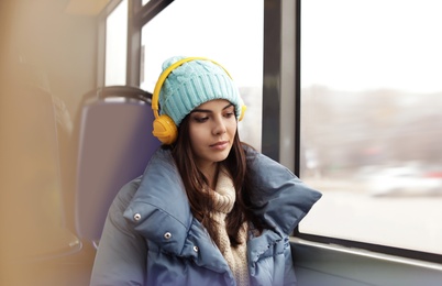 Photo of Young woman listening to music with headphones in public transport