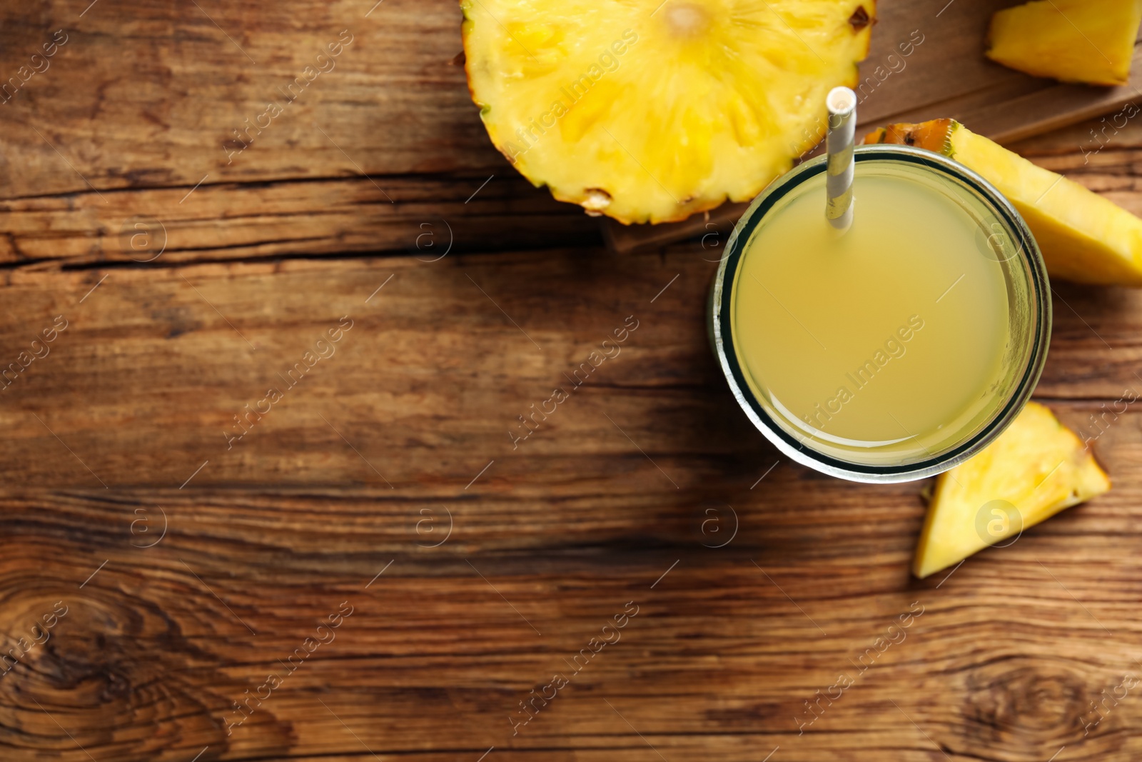 Photo of Delicious fresh pineapple juice on wooden table, flat lay. Space for text