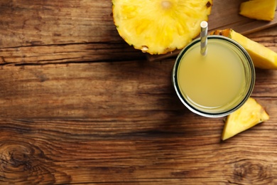 Photo of Delicious fresh pineapple juice on wooden table, flat lay. Space for text