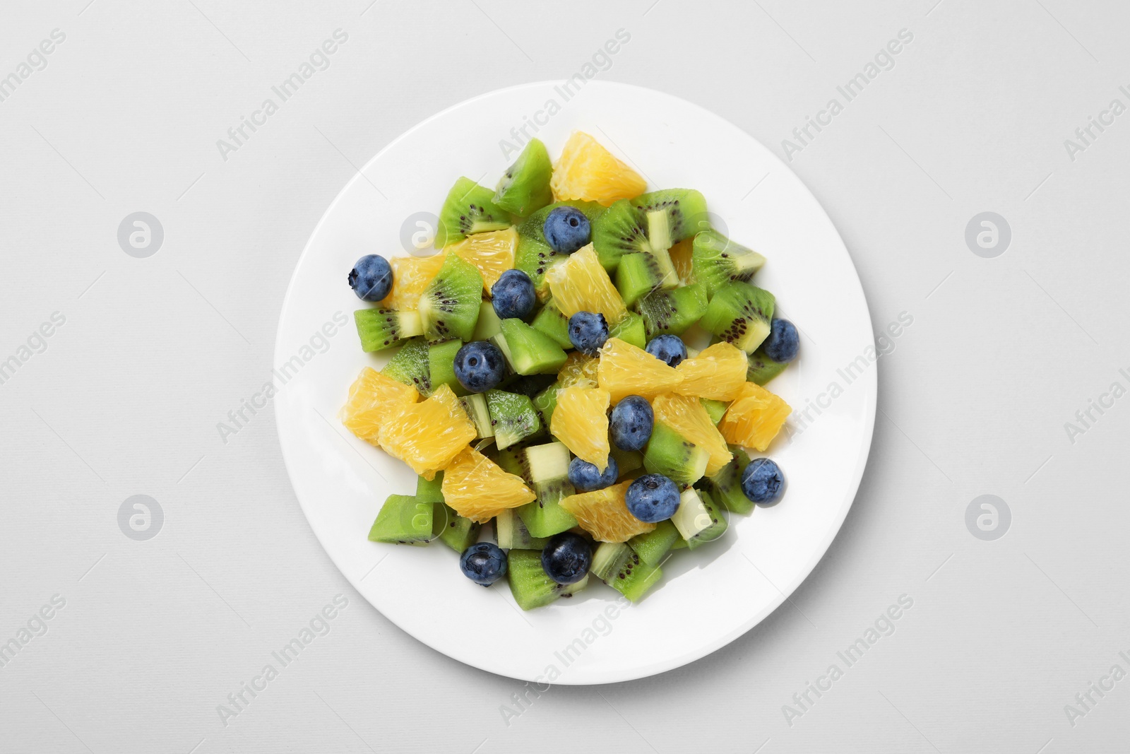 Photo of Plate of tasty fruit salad on light grey background, top view