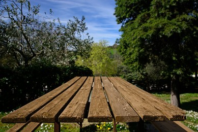 Photo of Empty wooden table in park on sunny day, space for text