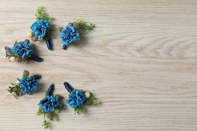 Photo of Stylish blue boutonnieres on white wooden table, flat lay. Space for text