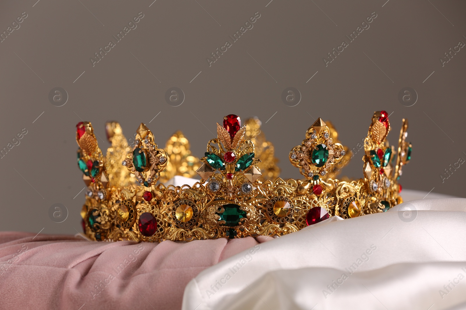 Photo of Beautiful gold tiara with gems on pink and white cloth
