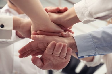 Photo of People holding hands together in office, closeup