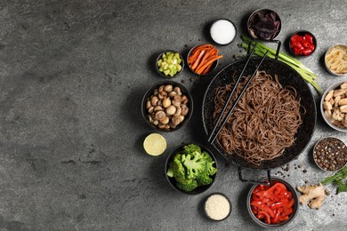 Photo of Wok with noodles, chicken and other products on grey table, flat lay. Space for text