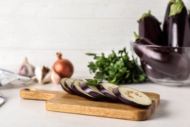 Photo of Cut ripe eggplant and basil on white wooden table