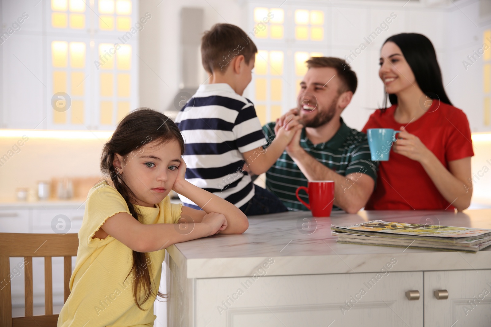 Photo of Unhappy little girl feeling jealous while parents spending time with her brother at home