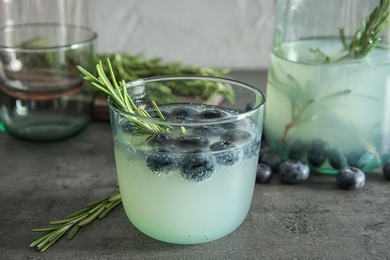 Glass of refreshing blueberry cocktail with rosemary on table
