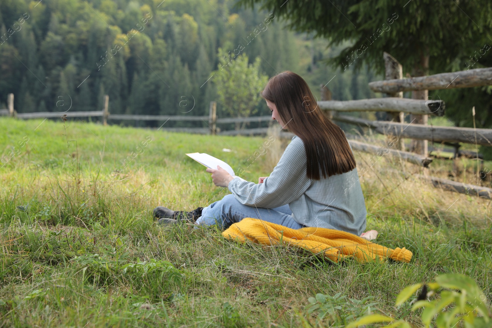 Photo of Beautiful young woman drawing with pencil in notepad on green grass