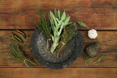 Mortar, different herbs and vegetables on wooden table, flat lay