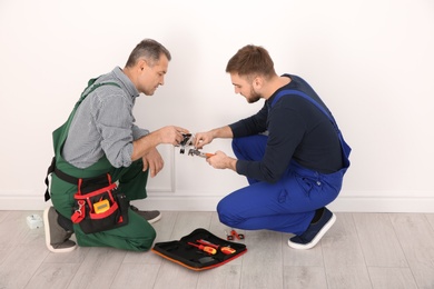 Electrician and apprentice working with wires indoors