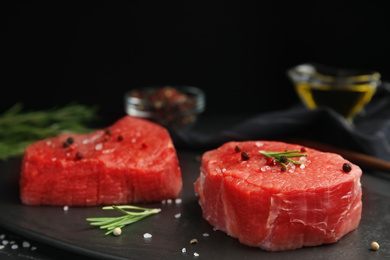 Photo of Fresh raw beef cut with spices on black table, closeup