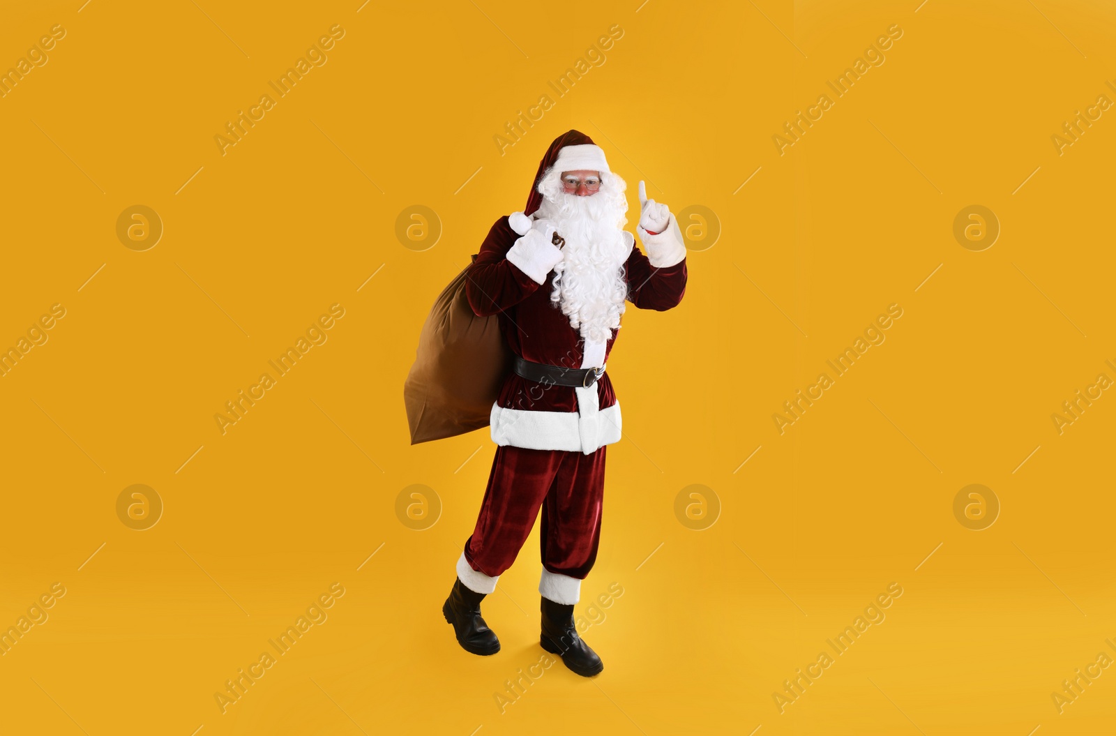 Photo of Full length portrait of Santa Claus with sack on yellow background