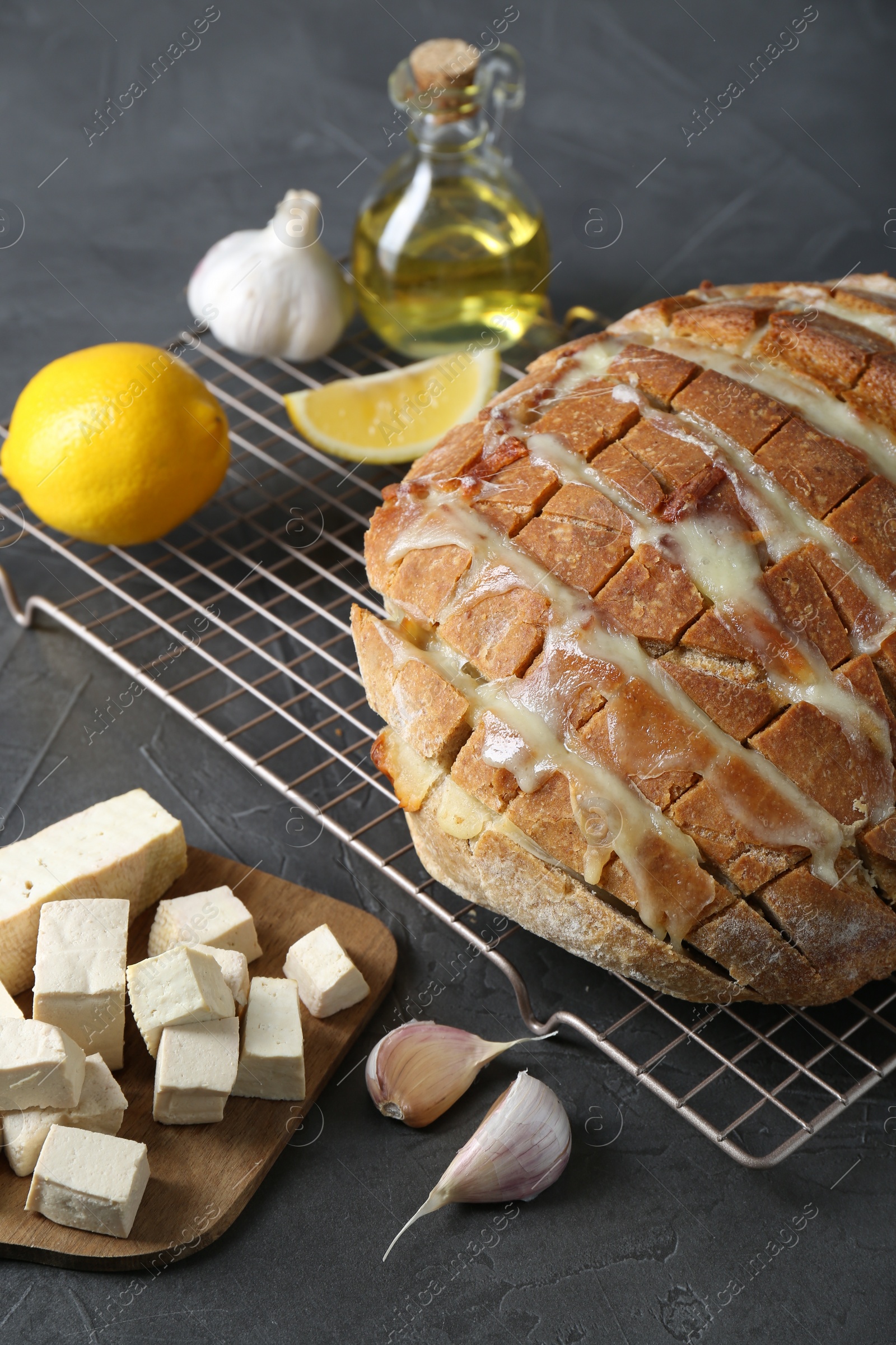 Photo of Freshly baked bread with tofu cheese and ingredients on black table