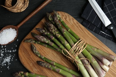 Photo of Fresh raw asparagus on black table, flat lay
