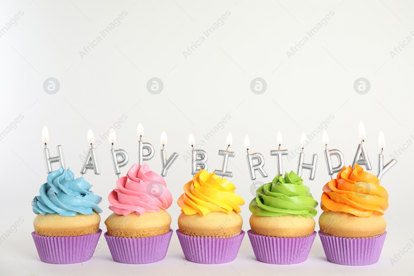 Photo of Birthday cupcakes with burning candles on white background