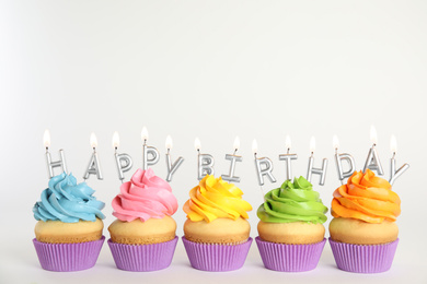 Birthday cupcakes with burning candles on white background