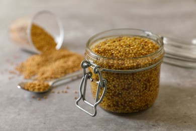 Jar of delicious whole grain mustard and seeds on grey table