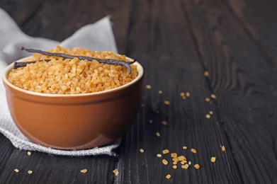 Photo of Bowl with brown vanilla sugar on wooden table