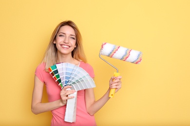 Photo of Young woman with color palette and roller on yellow background