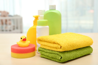 Photo of Baby cosmetic products, toy and towels on table indoors