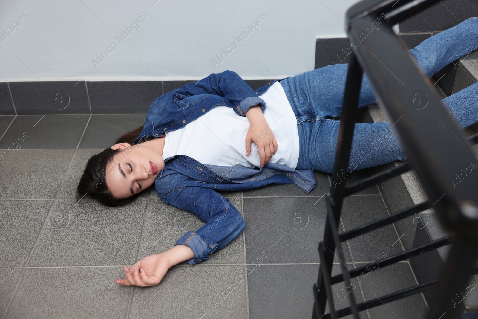 Photo of Unconscious woman lying on floor after falling down stairs indoors