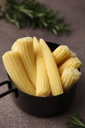 Tasty fresh yellow baby corns in dish on brown table