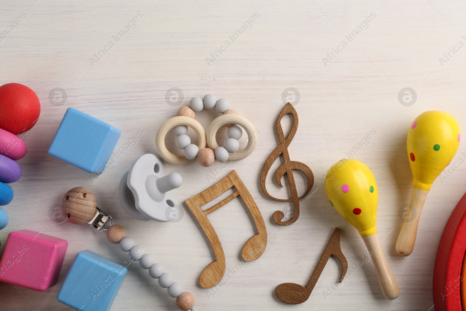 Photo of Baby song concept. Wooden notes, kids maracas and toys on table, flat lay. Space for text