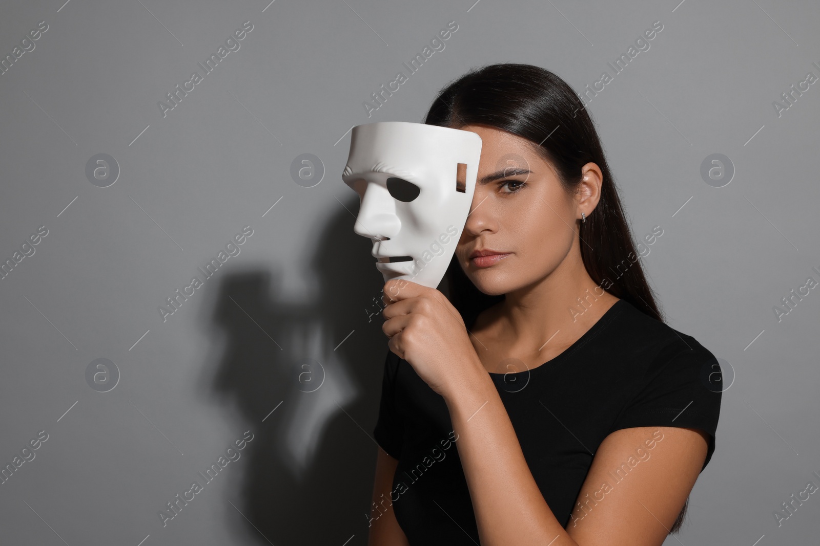 Photo of Multiple personality concept. Woman with mask on grey background, space for text