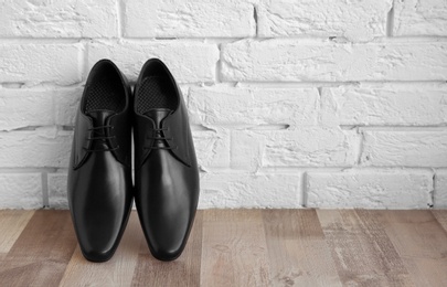 Photo of Elegant male shoes on floor near brick wall