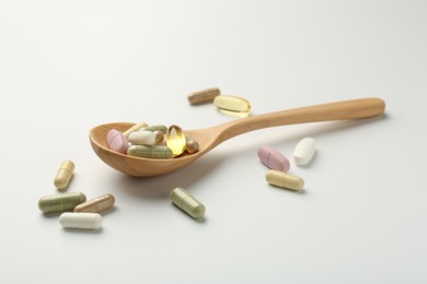 Photo of Different vitamin capsules in spoon on white background