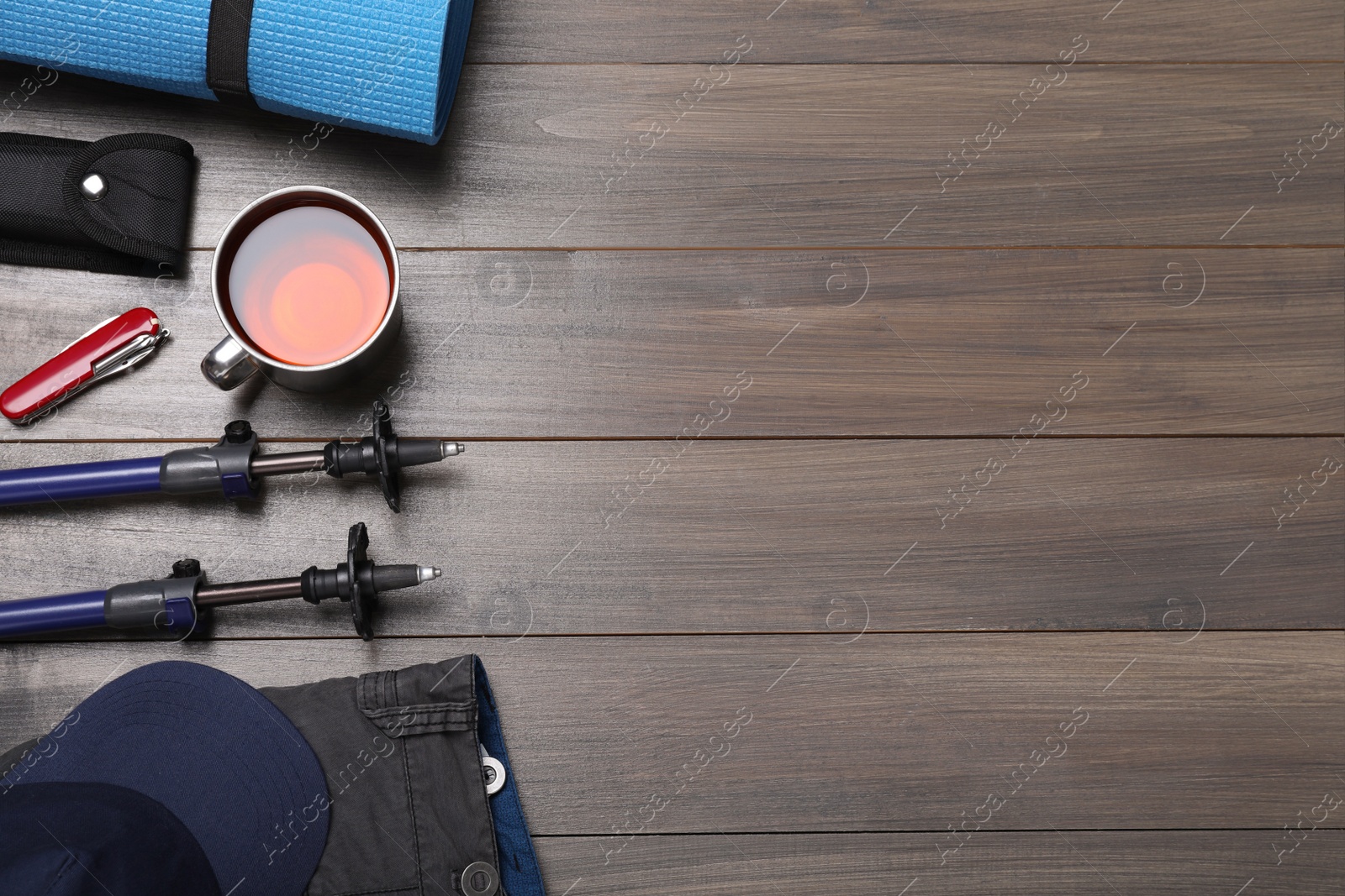 Photo of Flat lay composition with trekking poles and other hiking equipment on wooden background, space for text