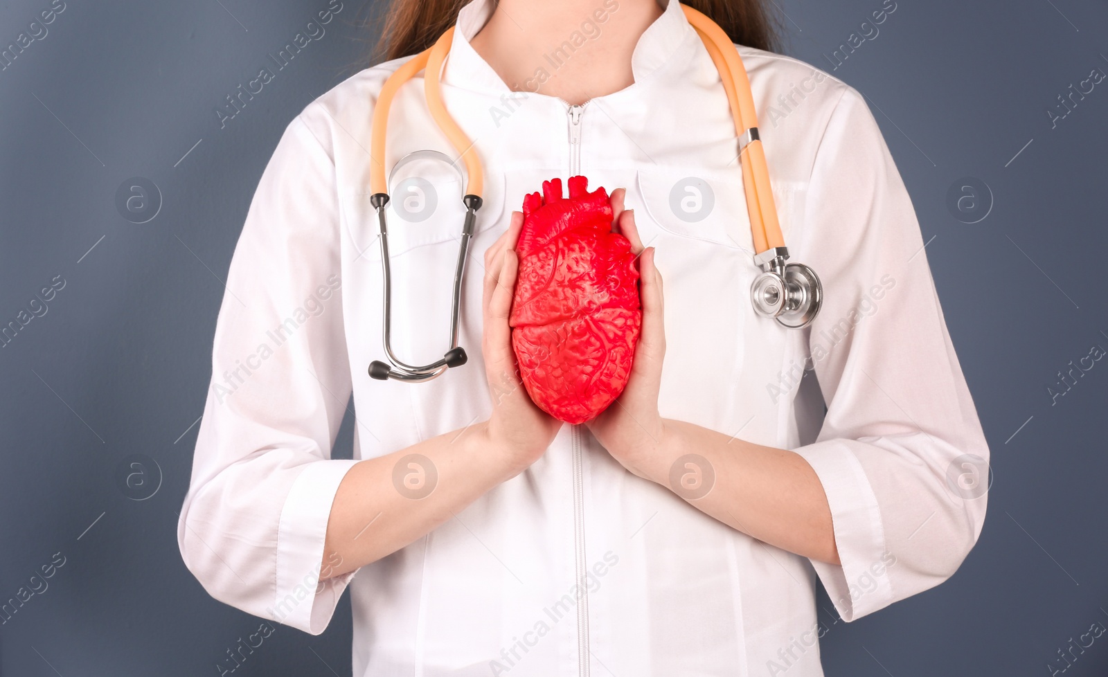 Photo of Doctor holding model of heart on color background. Prevent heart attack