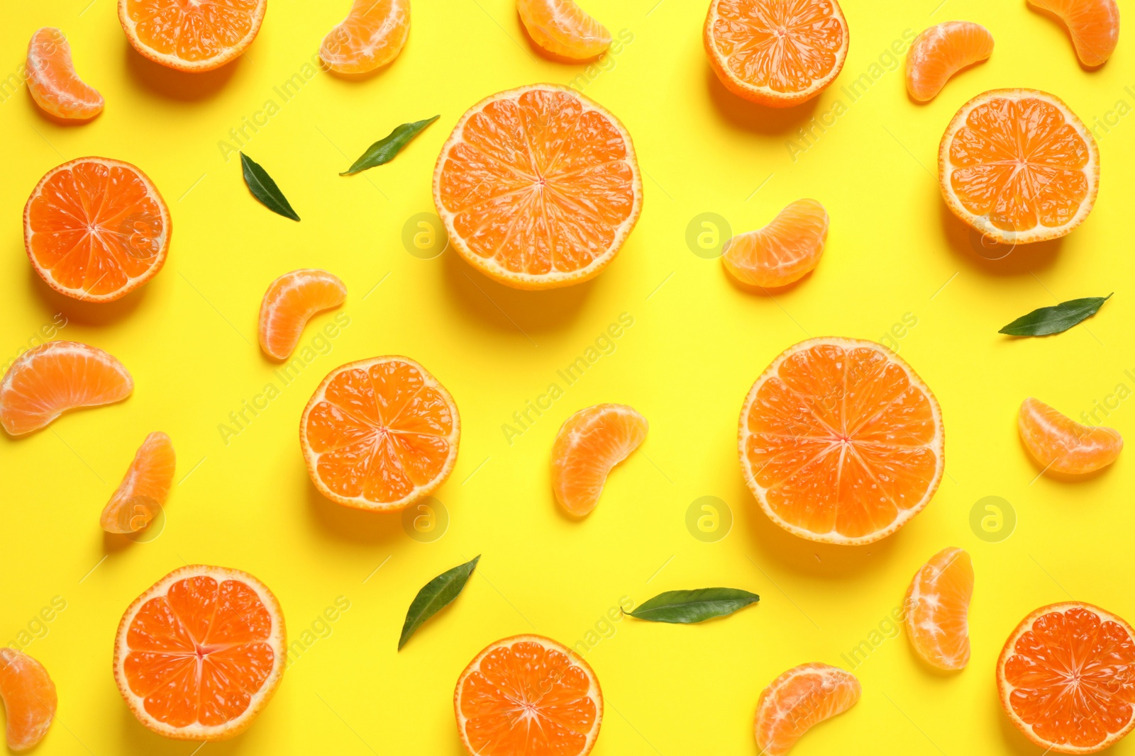 Photo of Flat lay composition with halves of fresh ripe tangerines and leaves on yellow background. Citrus fruit